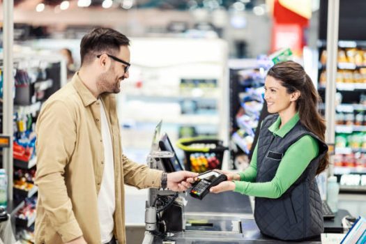 A customer paying with credit card at checkout in hypermarket. A customer paying with credit card at checkout in hypermarket.