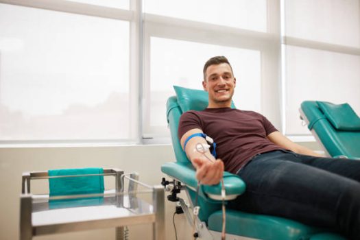 Young man lying while donating blood at the blood bank.