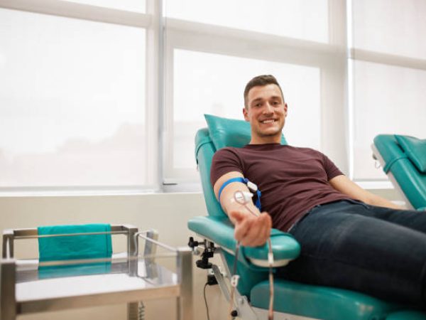 Young man lying while donating blood at the blood bank.