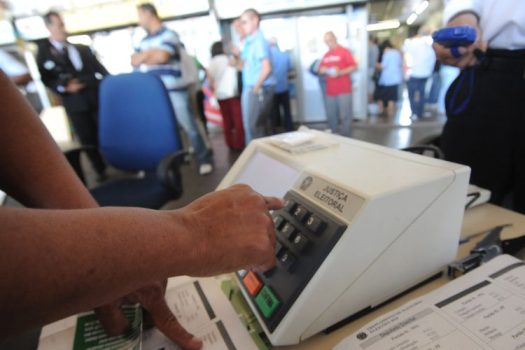 ELEITORES NA FILA E OUTRO VOTANDO