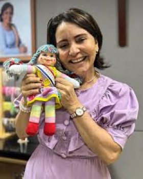 EMILIA CORREA COM UM BONECO NAS MÃOS RINDO DO POVO