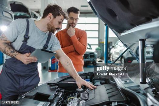 Auto mechanic explaining the problem to the customer while using digital tablet in a repair shop