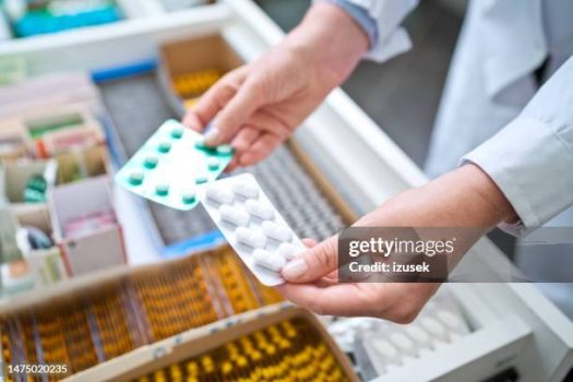 Pharmacists holding pills in hands above drawer with medicines. Close up of hands, unrecognizable person.