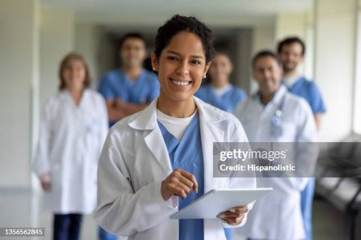 Happy female doctor leading a team of healthcare workers at the hospital and looking at the camera smiling