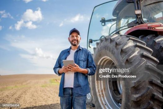 Portrait of farmer with tablet in front of his tractor