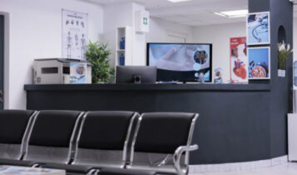 Clinic registration counter in waiting room lobby, computer to make checkup appointments with healthcare report papers. Empty hospital reception desk with medical forms and insurance support.