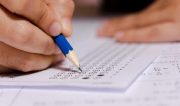 Students hand holding pencil writing selected choice on answer sheets and Mathematics question sheets. students testing doing examination. school exam