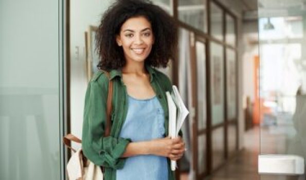 Young beautiful african girl student resting relaxing sitting in cafe smiling drinking coffee. Copy space.